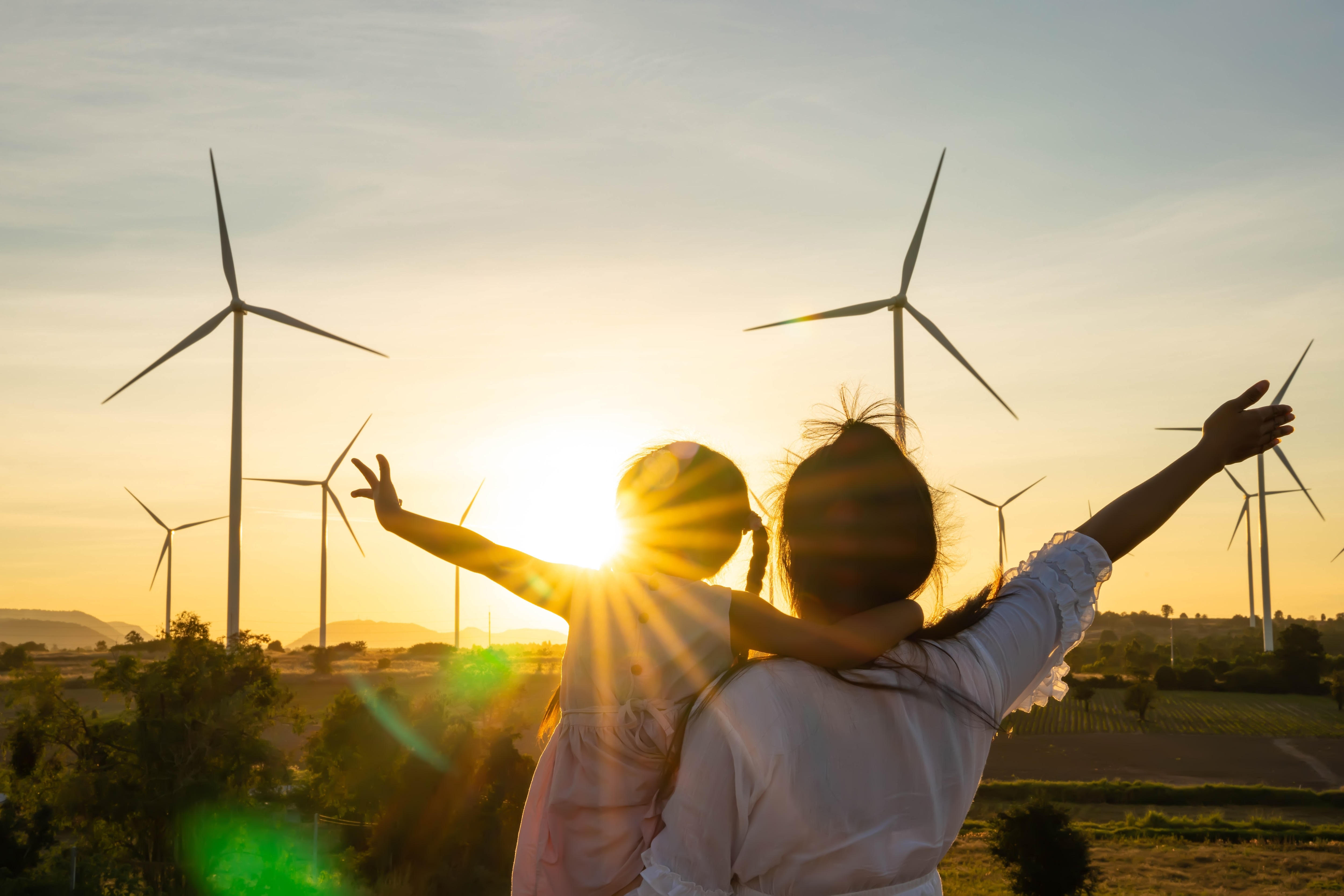 people looking at windmills at sunset.